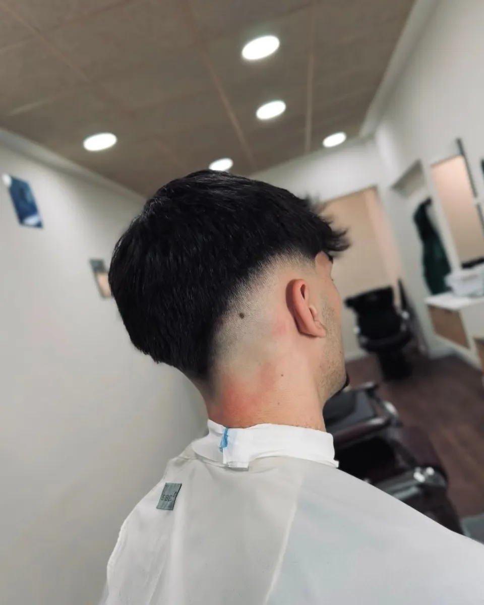 Degradado en los lados y la nuca, con el pelo negro y texturizado arriba
